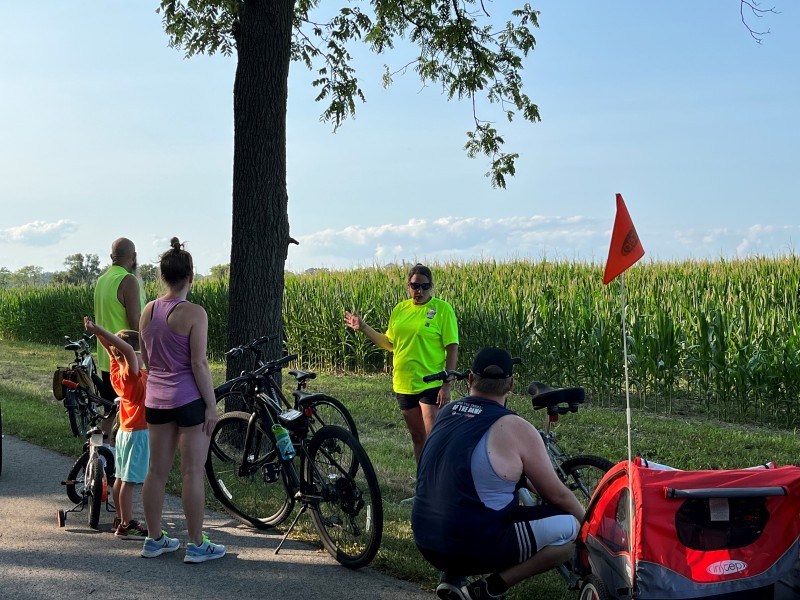 Cyclists along the North Coast Inland Trail listen to a presentation by Jannah Wilson, the executive director of the Park District of Ottawa County.